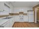 Bright kitchen featuring white appliances, cabinets, and modern countertops with wood-look floors at 11531 E Lovejoy Rd, Hampton, GA 30228