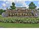 A sign reading WATERFALL with a water feature made of stones and shrubs in front of a business at 200 Deer Forest Trl, Fayetteville, GA 30214