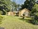 Lovely yellow house with stone accents and a well-manicured lawn, framed by tall trees and cloudy skies at 1327 Highway 54 E, Fayetteville, GA 30214