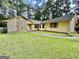 Charming home featuring a stone accent wall and yellow siding nestled among mature trees and a well-manicured lawn at 1327 Highway 54 E, Fayetteville, GA 30214