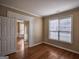 Inviting bedroom with hardwood floors, neutral walls, and a bright window, adjacent to an open doorway at 3028 Hallman Cir, Marietta, GA 30064