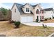View of the tan home showcasing a two-car garage and landscaped front yard at 2916 Ward Lake Way, Ellenwood, GA 30294