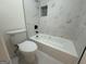 Bathroom with white tub, matching toilet, and marble-look tile at 115 Paces Way, Fayetteville, GA 30215