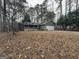 Quaint home with a front porch surrounded by trees and a yard covered with fallen leaves at 115 Paces Way, Fayetteville, GA 30215