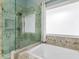Bathroom features an enclosed shower/tub with glass, neutral tile and a large window at 135 Oakpark Ter, Mcdonough, GA 30253