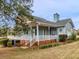 Large covered porch wraps around the home with brick base and white railing details at 135 Oakpark Ter, Mcdonough, GA 30253