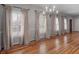 Living room with many windows dressed with curtains, hardwood floors and a chandelier at 135 Oakpark Ter, Mcdonough, GA 30253