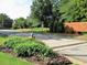 Street view of community entrance with flowerbeds, brick wall, landscaping, and mature trees at 135 Oakpark Ter, Mcdonough, GA 30253