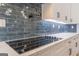 A close-up of a smooth cooktop on white quartz countertops with a blue subway tile backsplash at 2015 Fontainbleau Dr, Conyers, GA 30094