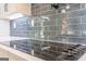 A close-up of a smooth cooktop on gray quartz countertops with a blue subway tile backsplash at 2015 Fontainbleau Dr, Conyers, GA 30094