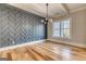 Modern living room with herringbone accent wall, wood floors, chandelier, and bright window at 2015 Fontainbleau Dr, Conyers, GA 30094