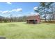 Red barn with a white trim, offering a rustic charm to the expansive green pasture at 757 Fischer Rd, Sharpsburg, GA 30277