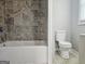 Bathroom featuring a tub with tiled wall surround and white toilet at 3930 W Side Pl, Ellenwood, GA 30294