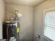 Utility room showcases a water heater next to a window with blinds, and visible plumbing at 3930 W Side Pl, Ellenwood, GA 30294