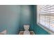 This half bathroom features light blue paint, tile floors, and a window at 100 Windmeadow Way, Fayetteville, GA 30214