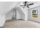 A bright, carpeted bedroom features angled ceilings and a ceiling fan, with a sunlit window offering scenic outdoor views at 130 Windchime Way # 9, Tyrone, GA 30290
