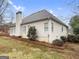 View of home's back exterior, with light siding, chimney, and landscaped yard at 9135 Woodhaven Way, Mcdonough, GA 30253