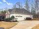 Exterior view of home, featuring an attached garage, stone accents, neutral siding and mature trees at 9135 Woodhaven Way, Mcdonough, GA 30253