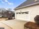 Attached two car garage with decorative windows, a driveway, and mature landscaping at 9135 Woodhaven Way, Mcdonough, GA 30253