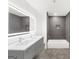 Modern bathroom features double vanity with sleek gray cabinets and bright, illuminated mirror and tiled shower and tub at 2692 Fairview Rd, Covington, GA 30016