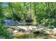 Beautiful waterfall cascading over rocks in a serene wooded area, a natural focal point on the property at 5200A Burruss Mill Rd, Cumming, GA 30041