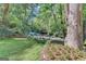 Landscaped backyard leading to a small waterfall, surrounded by lush greenery and shade trees at 5200A Burruss Mill Rd, Cumming, GA 30041