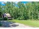 Scenic view of a two-story house with a red roof on expansive green lot surrounded by lush trees, serene setting at 5200A Burruss Mill Rd, Cumming, GA 30041
