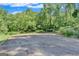 Spacious gravel lot surrounded by trees, complemented by manicured lawn and a small wooden structure in background at 5200A Burruss Mill Rd, Cumming, GA 30041