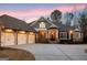 Inviting single-story home with a three-car garage, covered porch, and a circular driveway at sunset at 545 Mountains Edge, Peachtree City, GA 30269