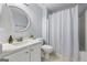 Bathroom with a framed round mirror, shower with curtain, and a decorative plant at 410 Mockingbird Dr, Loganville, GA 30052
