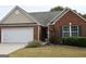 Brick front home featuring a two-car garage, manicured lawn, and well-maintained landscaping around the entrance at 410 Mockingbird Dr, Loganville, GA 30052