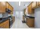 Modern kitchen boasting stainless steel appliances, black countertops, wood cabinets, and tile flooring at 410 Mockingbird Dr, Loganville, GA 30052