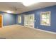 Finished basement with blue walls, carpet, a ceiling fan, and a set of glass doors at 401 Robinson Rd, Peachtree City, GA 30269