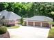 Spacious brick home featuring a large three-car garage, ample driveway space, and a lush, wooded backdrop at 401 Robinson Rd, Peachtree City, GA 30269
