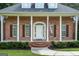 Close-up of a brick home's front entrance featuring a columned porch and an American flag at 401 Robinson Rd, Peachtree City, GA 30269