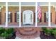 Close-up of a brick home's columned front porch featuring an arched entrance and an American flag at 401 Robinson Rd, Peachtree City, GA 30269