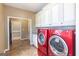 Bright laundry room with custom cabinetry, granite countertops, and red front load washer and dryer at 401 Robinson Rd, Peachtree City, GA 30269