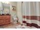Bathroom with a single vanity, wood cabinets, tiled floors, shower with curtain, and decorative painting at 115 Foxford Run, Tyrone, GA 30290