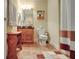 Bathroom with a single vanity, wood cabinets, tiled floors, shower with curtain, and decorative painting at 115 Foxford Run, Tyrone, GA 30290