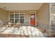 Inviting front porch with rocking chairs, stone accents, and a decorative red front door at 115 Foxford Run, Tyrone, GA 30290