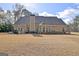 Rear exterior showcasing a large home with a well-manicured lawn and an outdoor patio area at 115 Foxford Run, Tyrone, GA 30290