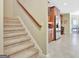 Carpeted staircase leading to an open kitchen area with stainless appliances and a window for natural light at 115 Foxford Run, Tyrone, GA 30290