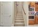 Carpeted staircase with wooden handrail leads to the upper level, adjacent to the kitchen appliances and a white door at 115 Foxford Run, Tyrone, GA 30290