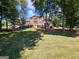 Expansive backyard showcasing the home's architecture, lush landscaping and mature trees at 125 Turnberry Cir, Fayetteville, GA 30215