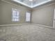Bedroom showcases a tray ceiling, plush carpeting, and natural light from a window at 125 Turnberry Cir, Fayetteville, GA 30215