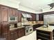 A chef's kitchen with dark wood cabinetry, granite counters, and stainless steel appliances at 125 Turnberry Cir, Fayetteville, GA 30215