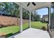 View of the covered patio with ceiling fan overlooking the lush green lawn and wooded area of the backyard at 4368 Burton Bend Way, Buford, GA 30518