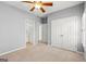 Neutral bedroom featuring a ceiling fan, double closets, and hallway and bathroom doorways at 44 Star Spangled Ln, Peachtree City, GA 30269