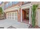 Close-up of a brick townhome showcasing the front entry, attached garage and detailed trim and well manicured landscaping at 44 Star Spangled Ln, Peachtree City, GA 30269
