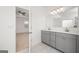 Elegant bathroom featuring double sinks, gray cabinets, and a large mirror; bedroom doorway visible at 1724 Goodwin Dr # 74, Hampton, GA 30228